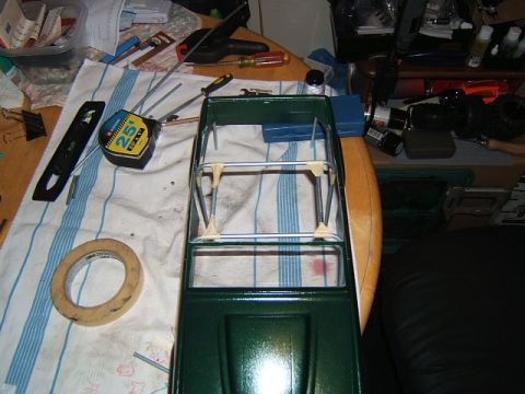 1988 Ford Bronco - A partially assembled model car chassis sits on a workbench with various tools and supplies.