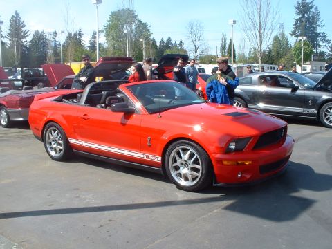 2000 Ford Crown Victoria - A red convertible sports car is parked at an outdoor car show with other vehicles.