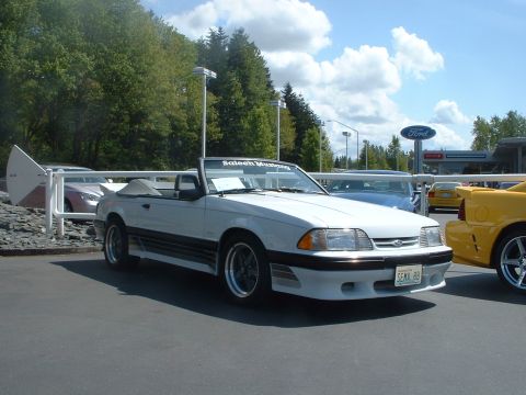 2000 Ford Crown Victoria - A white 1989 Saleen Mustang convertible is parked in front of a Ford dealership.