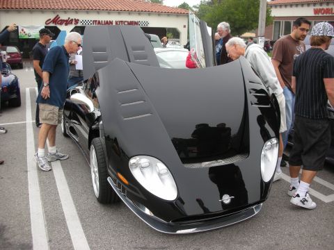 1998 Ford Crown Victoria - low black supercar with its clamshell front hood raised draws onlookers in a parking lot outside an Italian restaurant.