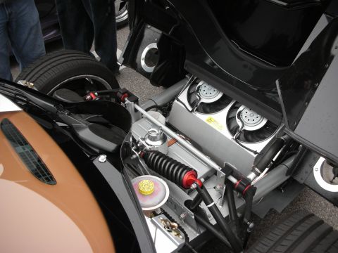 1998 Ford Crown Victoria - Engine-bay detail of a black supercar showing polished suspension links, coilovers and twin circular air intakes.