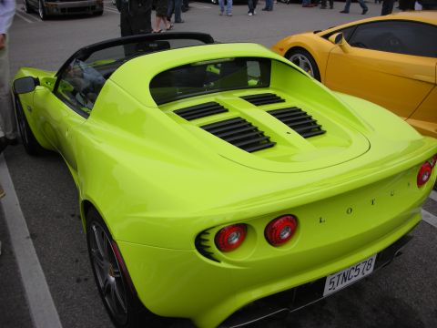 1998 Ford Crown Victoria - Rear view of a lime-green Lotus Elise roadster with louvered engine cover and round taillights, parked beside a yellow car.