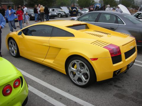 1998 Ford Crown Victoria - Side rear view of a yellow Lamborghini Gallardo coupe with five-spoke wheels parked among cars at an outdoor show.