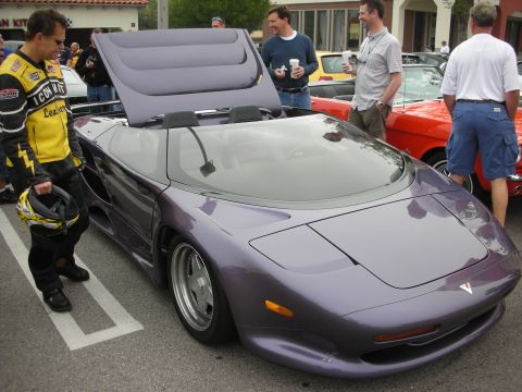 1998 Ford Crown Victoria - metallic purple wedge-shaped Vector convertible supercar with engine cover raised on display at an outdoor car show.