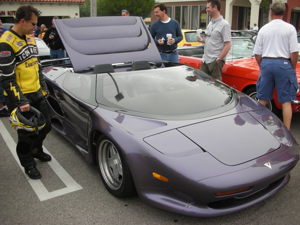 Purple Vector supercar convertible with raised hood at car show