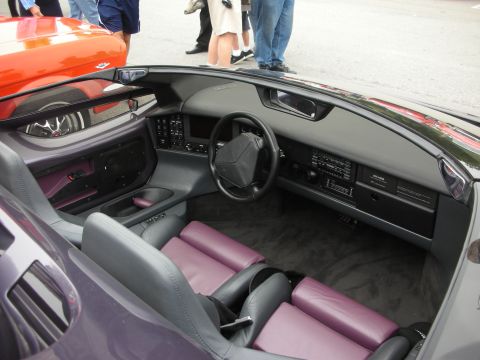 1998 Ford Crown Victoria - Interior of a wedge-shaped supercar showing gray dash, three-spoke wheel and gray-and-purple leather seats.