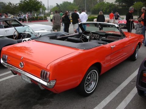 1998 Ford Crown Victoria - orange early Ford Mustang convertible with top down sits in a parking lot among other classic cars at a show.
