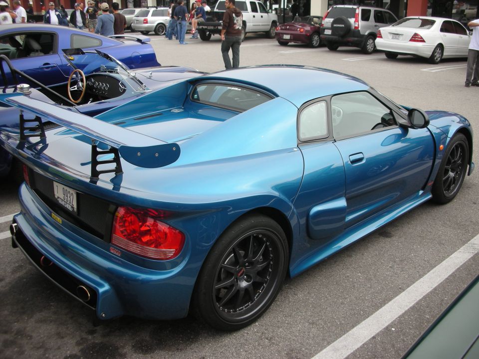 Blue Noble mid-engine sports car rear three-quarter with large wing