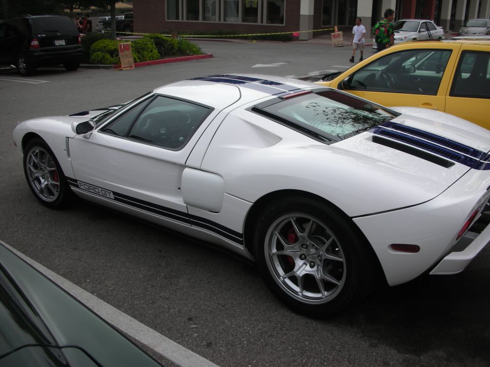 White Ford GT with blue stripes parked side profile beside a yellow car