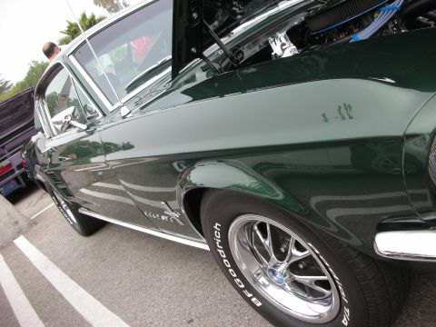 1998 Ford Crown Victoria - Close low angle of a dark green classic Mustang fastback's front fender, chrome wheel and BFGoodrich tire.