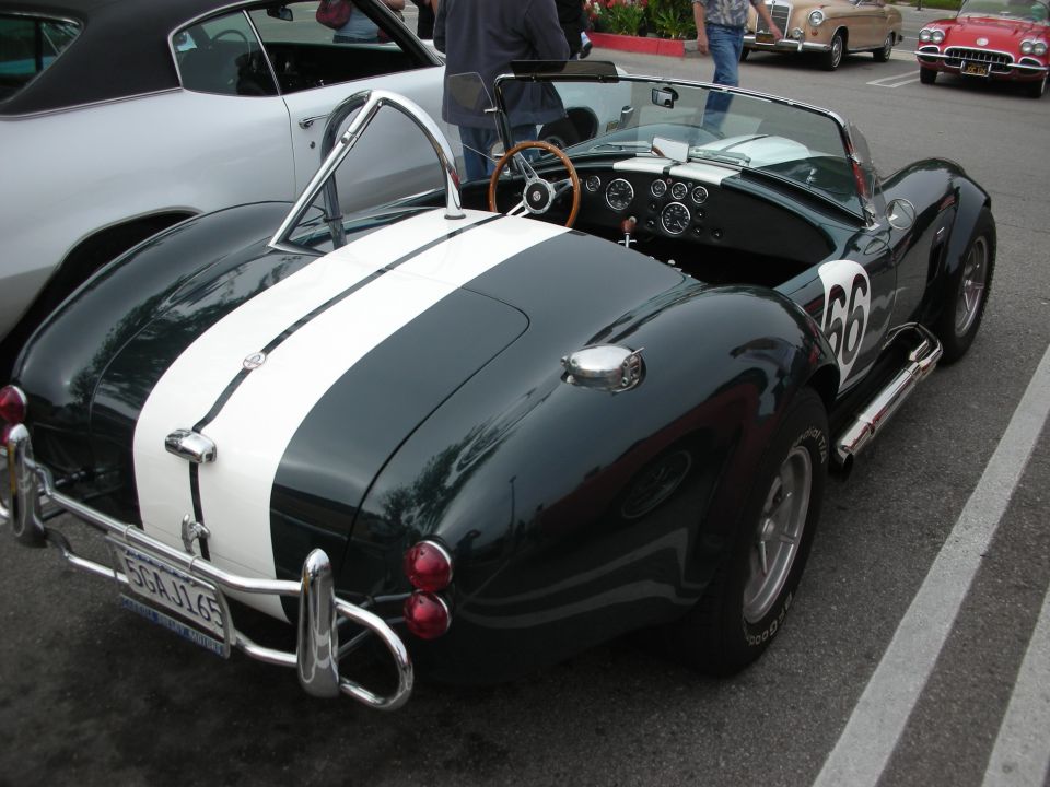 Dark green Shelby Cobra roadster with white stripe and number 66 rear view