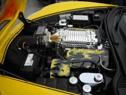 1998 Ford Crown Victoria - yellow Corvette's engine bay features a polished supercharger and airbrushed flame-and-skull artwork on the covers.