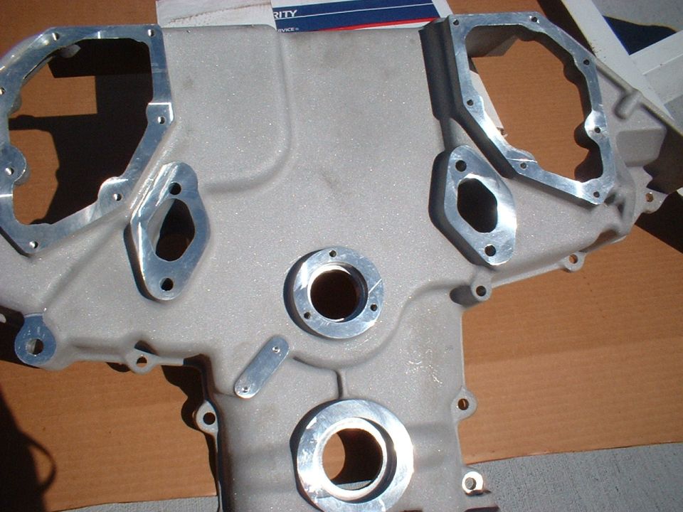 Cast aluminum V-engine timing cover with machined mating surfaces sitting on cardboard