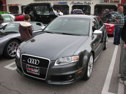 1998 Ford Crown Victoria - gray Audi RS4 sedan sits front three-quarter in a parking lot car show with a dealer plate and spectators nearby.