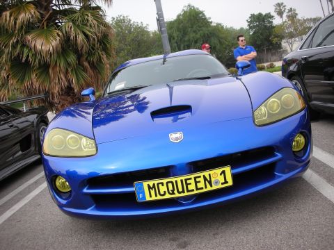 1998 Ford Crown Victoria - blue Dodge Viper shows its front fascia and yellow MCQUEEN 1 plate with two men standing behind it at a show.