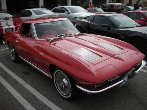1998 Ford Crown Victoria - red mid-1960s Corvette Sting Ray coupe with chrome bumpers and hood louvers parked at a car show.