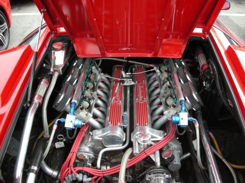 1998 Ford Crown Victoria - open engine bay of a red sports car revealing a V12 engine with red intake covers, polished pipes, and red plug wires.