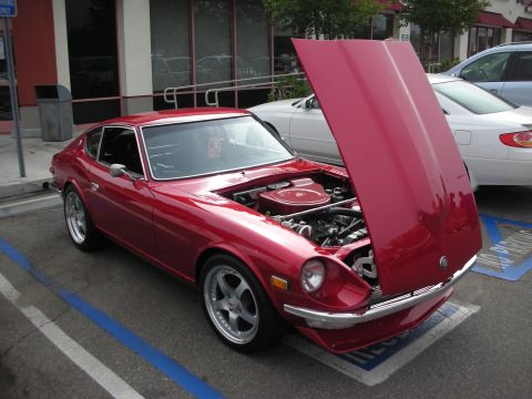 1998 Ford Crown Victoria - dark red Datsun Z-car coupe with chrome bumpers and its hood raised, parked in a handicap-marked spot.