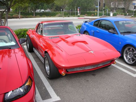 1998 Ford Crown Victoria - red mid-1960s Corvette Sting Ray with hood louvers parked in a lot between a red and a blue Mustang.
