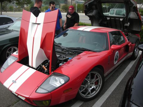 1998 Ford Crown Victoria - red Ford GT with white racing stripes and the number 48, its clamshell hood and door open as onlookers gather at a show.