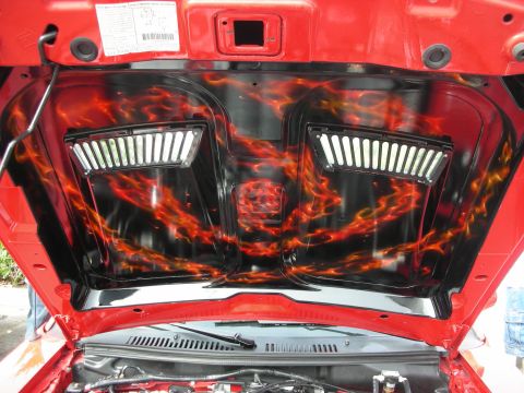 1998 Ford Crown Victoria - underside of a raised red hood featuring orange-and-black airbrushed flame artwork around two louvered vent panels.