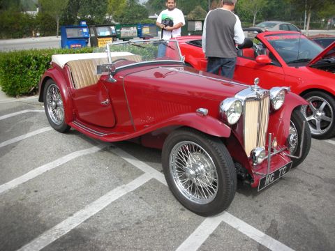 1998 Ford Crown Victoria - dark red prewar-style MG roadster with chrome wire wheels and an MG TC plate, parked among other cars at a show.