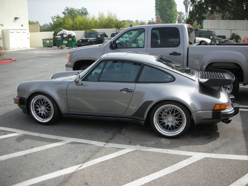 Silver-grey Porsche 911 Turbo with whale-tail spoiler, side profile in a lot