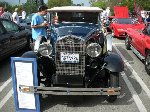 1998 Ford Crown Victoria - Front view of a black 1930s vintage car with a tall chrome grille and round headlights, California plate 5GZS924, at a car show.