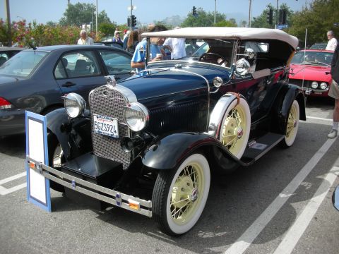 1998 Ford Crown Victoria - black vintage Ford Model A open phaeton with a tan top and yellow-painted wire wheels, California plate 5GZS924, at a show.