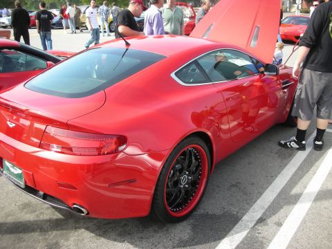 1998 Ford Crown Victoria - Rear three-quarter view of a red Aston Martin V8 Vantage coupe on black multispoke wheels with its door open in a parking lot.