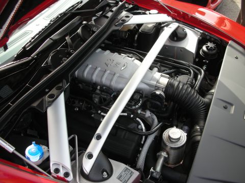 1998 Ford Crown Victoria - Close-up of a 4.3-liter V8 engine in a red Aston Martin engine bay with a painted strut brace and coolant reservoir.