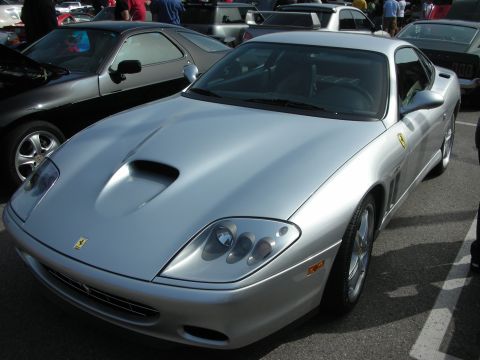 1998 Ford Crown Victoria - Front three-quarter view of a silver Ferrari coupe with a hood scoop and prancing-horse badges parked at an outdoor show.