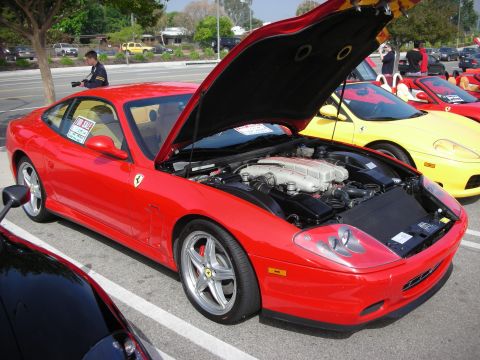 1998 Ford Crown Victoria - red Ferrari grand-touring coupe with its hood raised, displaying a front-mounted V12 engine among rows of Ferraris.