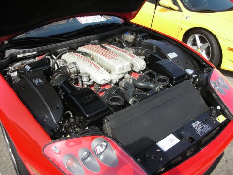 1998 Ford Crown Victoria - Engine bay of a red Ferrari showing a front-mounted V12 with red-painted intake plenum and twin air boxes.