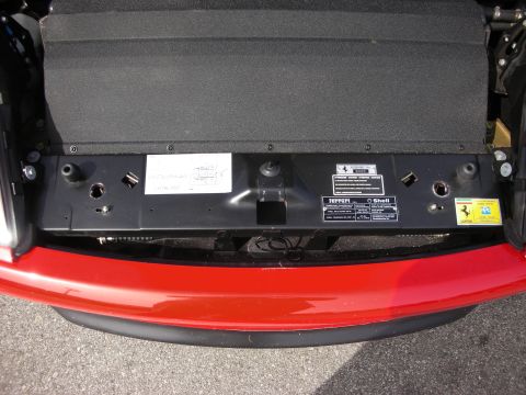 1998 Ford Crown Victoria - open front trunk area of a red Ferrari revealing chassis data plates, a Ferrari shield and a Shell sticker.