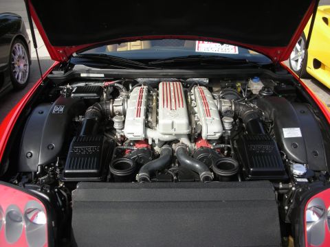 1998 Ford Crown Victoria - Top-down view of a red Ferrari's front-mounted V12 engine with red-striped plenum, twin air boxes and red taillights below.