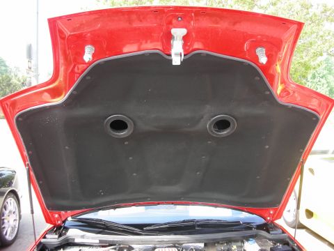 1998 Ford Crown Victoria - View of the underside of a red car's raised hood showing a black insulation liner with two round vent grommets.