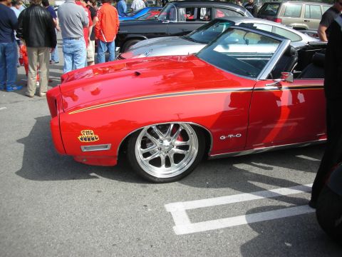1998 Ford Crown Victoria - Rear three-quarter view of a red Pontiac GTO 'The Judge' convertible showing its decal and chrome multispoke wheel.