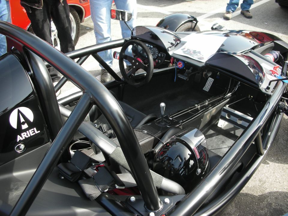 Cockpit of black Ariel Atom showing steering wheel and helmet