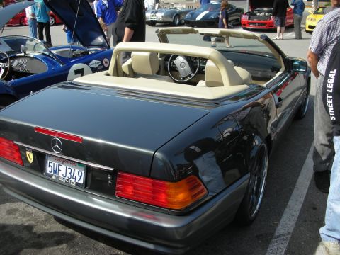 1998 Ford Crown Victoria - Rear three-quarter view of a black Mercedes-Benz SL convertible with tan interior parked among cars at a show.