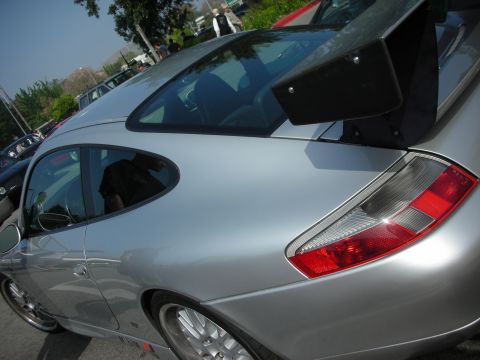 1998 Ford Crown Victoria - Close-up of the rear quarter, taillight and wing of a silver Porsche 911 coupe.
