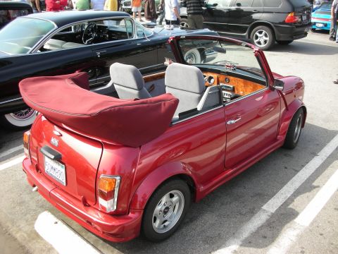1998 Ford Crown Victoria - dark red Mini convertible with gray seats and a wood-trim dash parked at a car show.