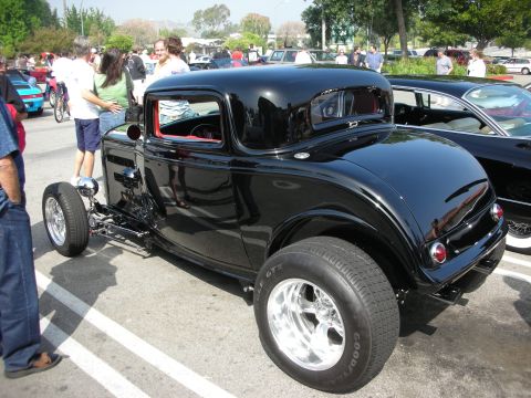 1998 Ford Crown Victoria - black three-window hot rod coupe with exposed front suspension and chrome wheels at a car show.