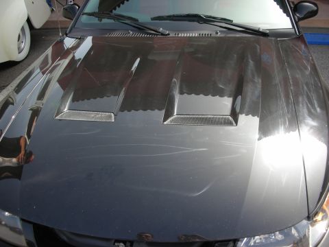 1998 Ford Crown Victoria - Close-up of a black car hood featuring twin recessed heat-extractor vents and the windshield cowl.