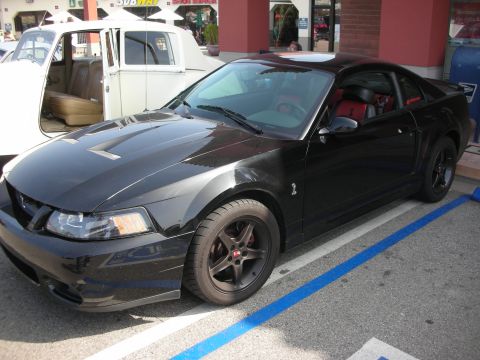 1998 Ford Crown Victoria - black New Edge Ford Mustang Cobra with red interior and dark wheels parked at a show.