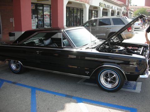 1998 Ford Crown Victoria - black Plymouth Belvedere hardtop with redline-style tires and the hood raised, parked at a show.