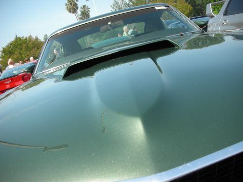 1998 Ford Crown Victoria - Close-up of a dark green Mustang's hood scoop, windshield and reflections at a car show.