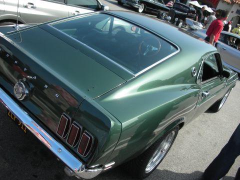 1998 Ford Crown Victoria - Rear-quarter view of a dark green Ford Mustang fastback with body-side MUSTANG lettering at a show.