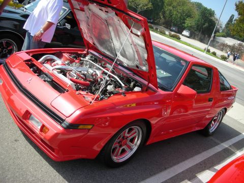 1998 Ford Crown Victoria - Front-quarter view of a red 1980s turbo sports coupe with its hood raised over the engine bay.