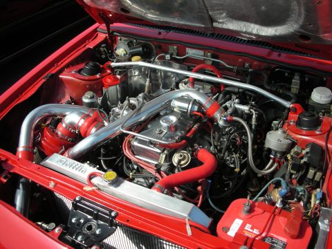 1998 Ford Crown Victoria - Detailed engine bay of a red car showing a large turbocharger, polished piping and red hoses.